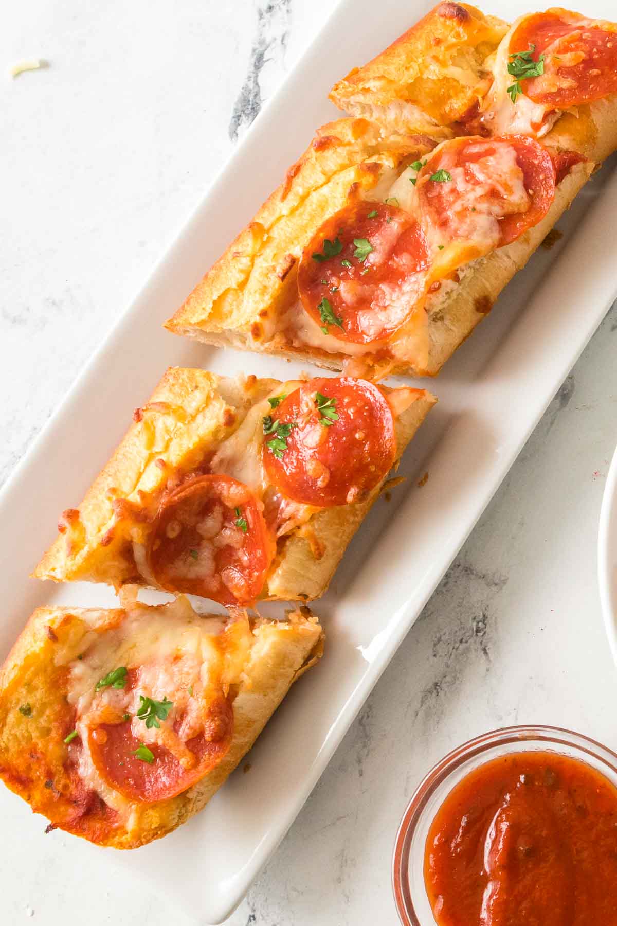 Garlic bread pizza sliced on a plate with marinara sauce on the side