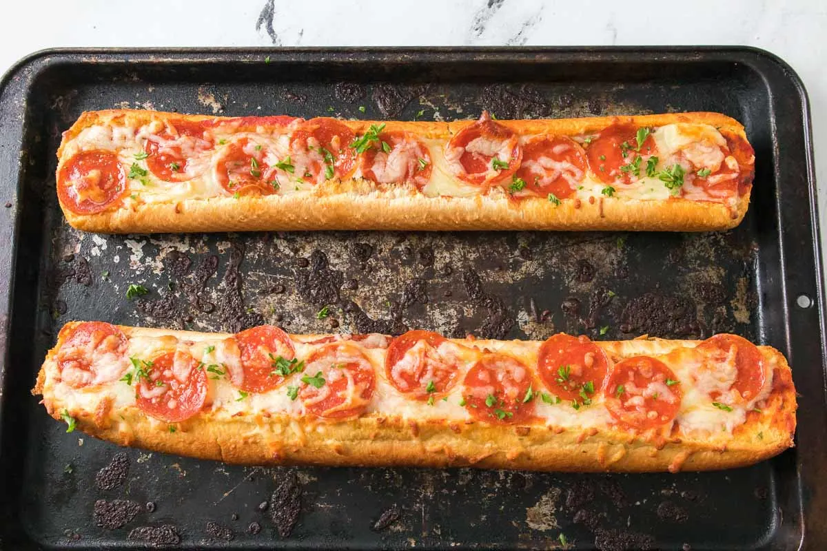 Baked garlic bread pizza with pepperoni on a baking sheet