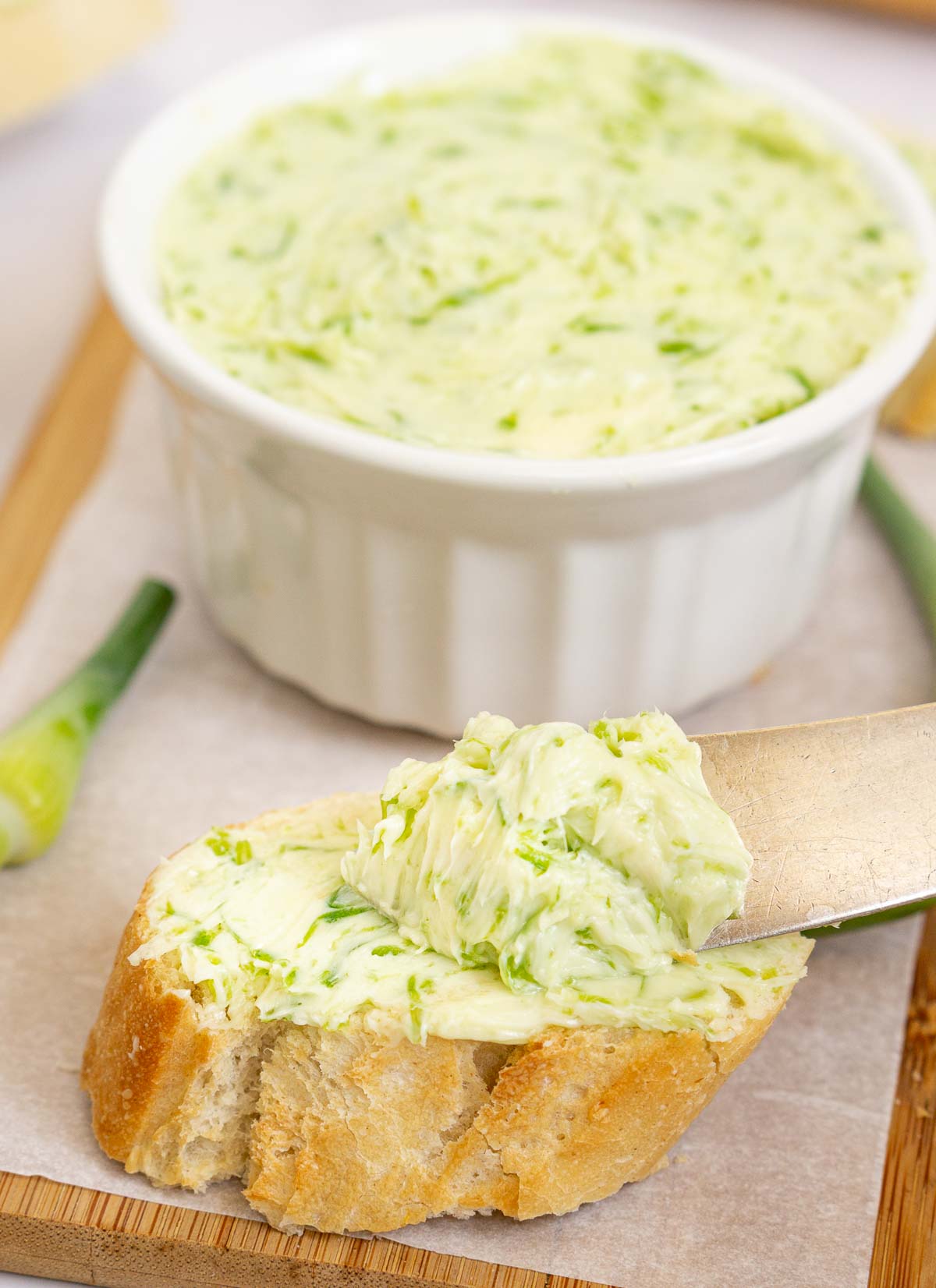 Spreading garlic scape butter on a baguette