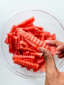 Hand showing how watermelon fries should be cut