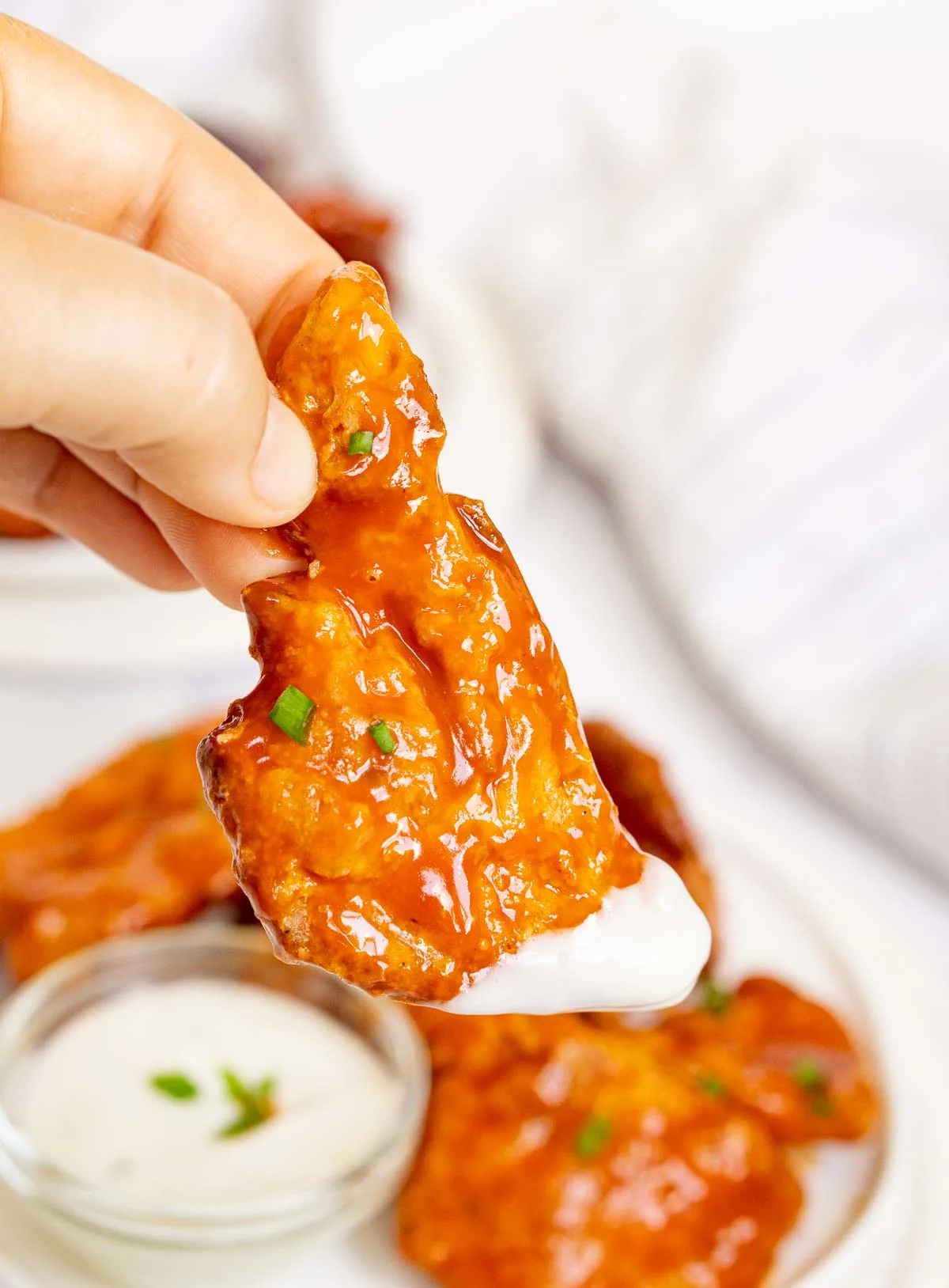 Hand holding piece of Chicken of the Wood Mushroom "wing" coated in Buffalo sauce