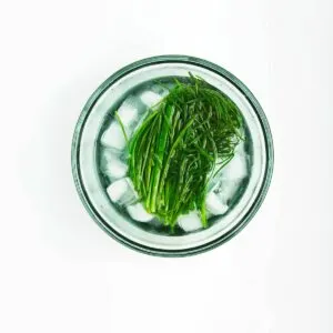 Blanched chives in an ice bath bowl