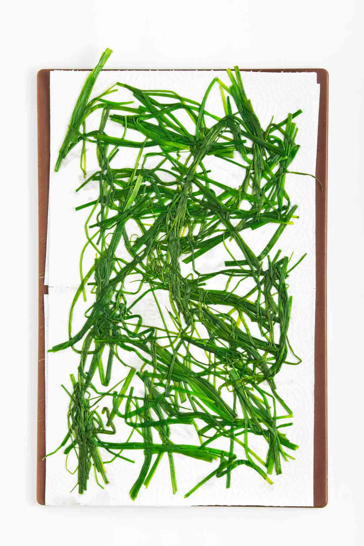 Blanched chives drying on a paper towel