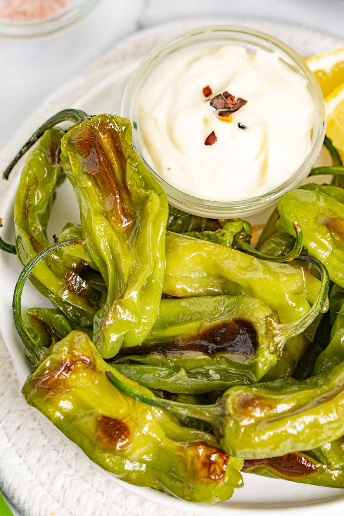 Roasted shishito peppers on a plate with truffle mayo sauce