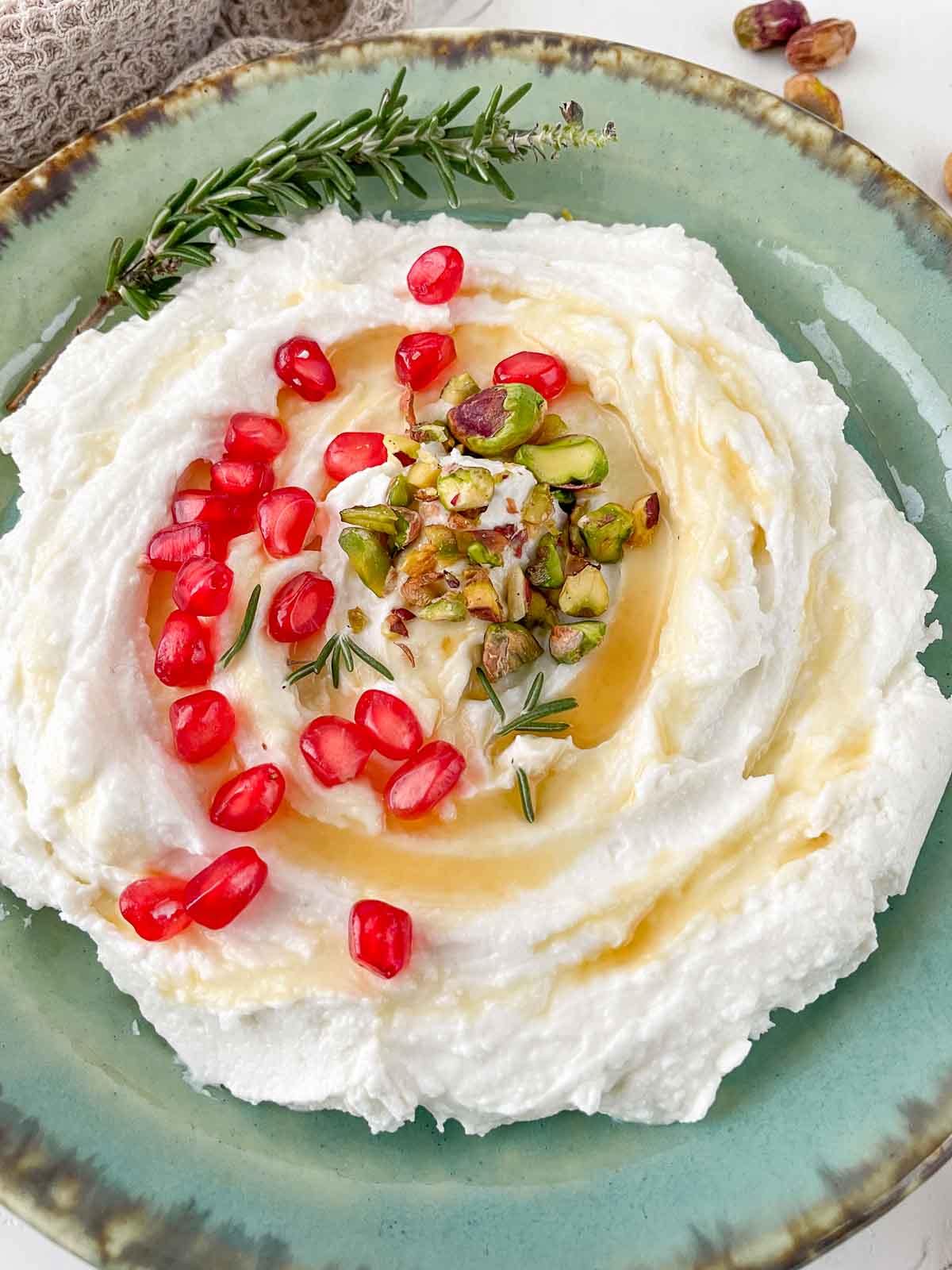 Bowl of whipped goat cheese dip with honey, pistachios, and pomegranate
