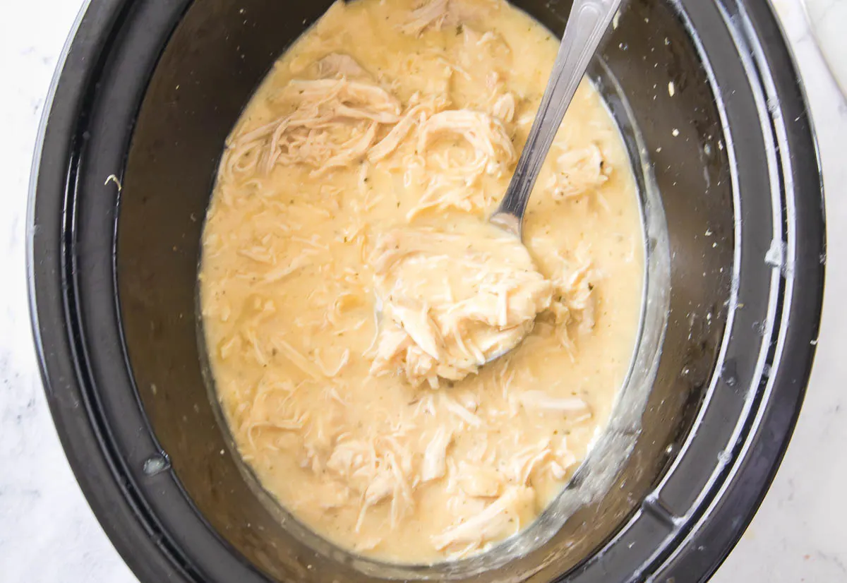 Shredded chicken in creamy gravy in a slow cooker.