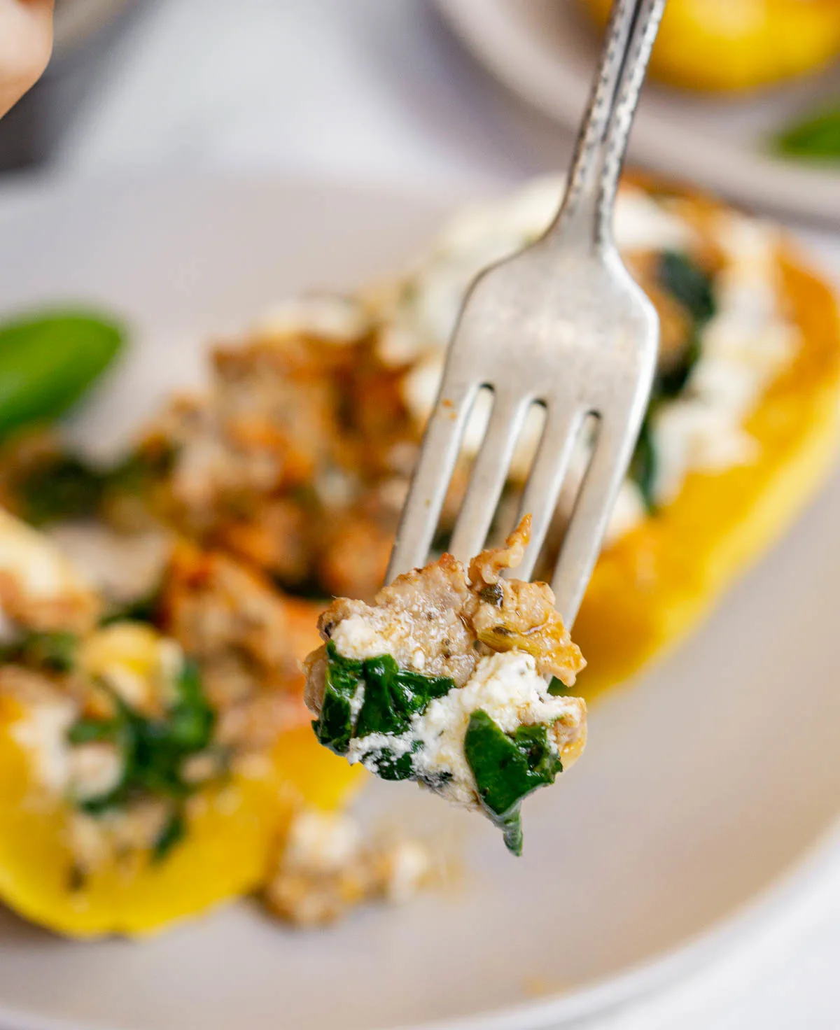 Piece of cooked Italian sausage, ricotta, and spinach on a fork.