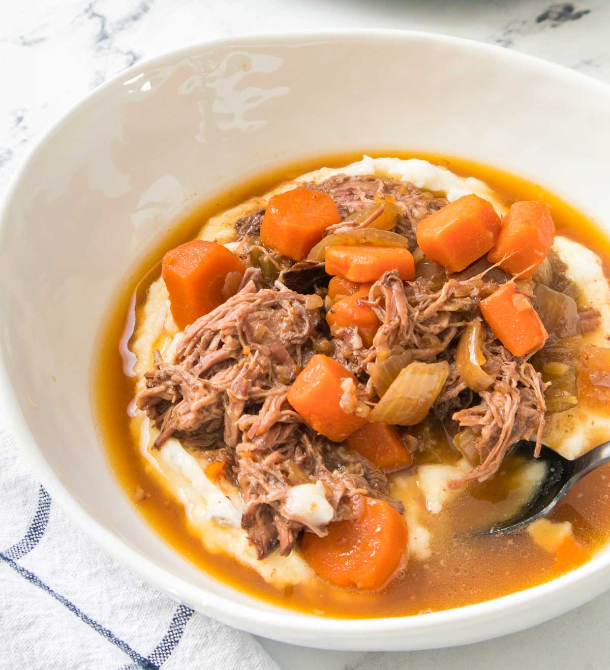 Pot roast served over mashed potatoes in a bowl