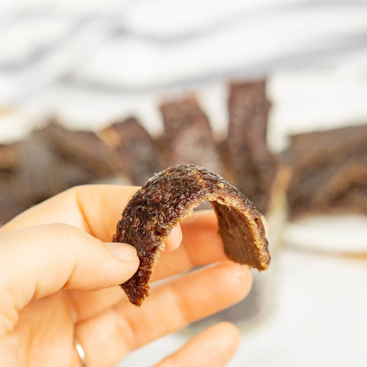 Bending a piece of ground beef jerky to show how soft it is