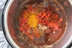 Broth, seasonings, and diced tomatoes added to chili in the Instant Pot