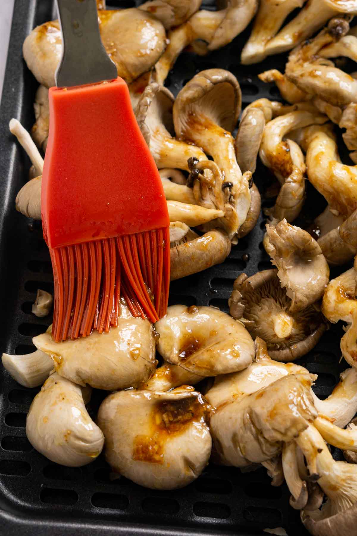 Brushing on soy sauce seasoning on oyster mushrooms