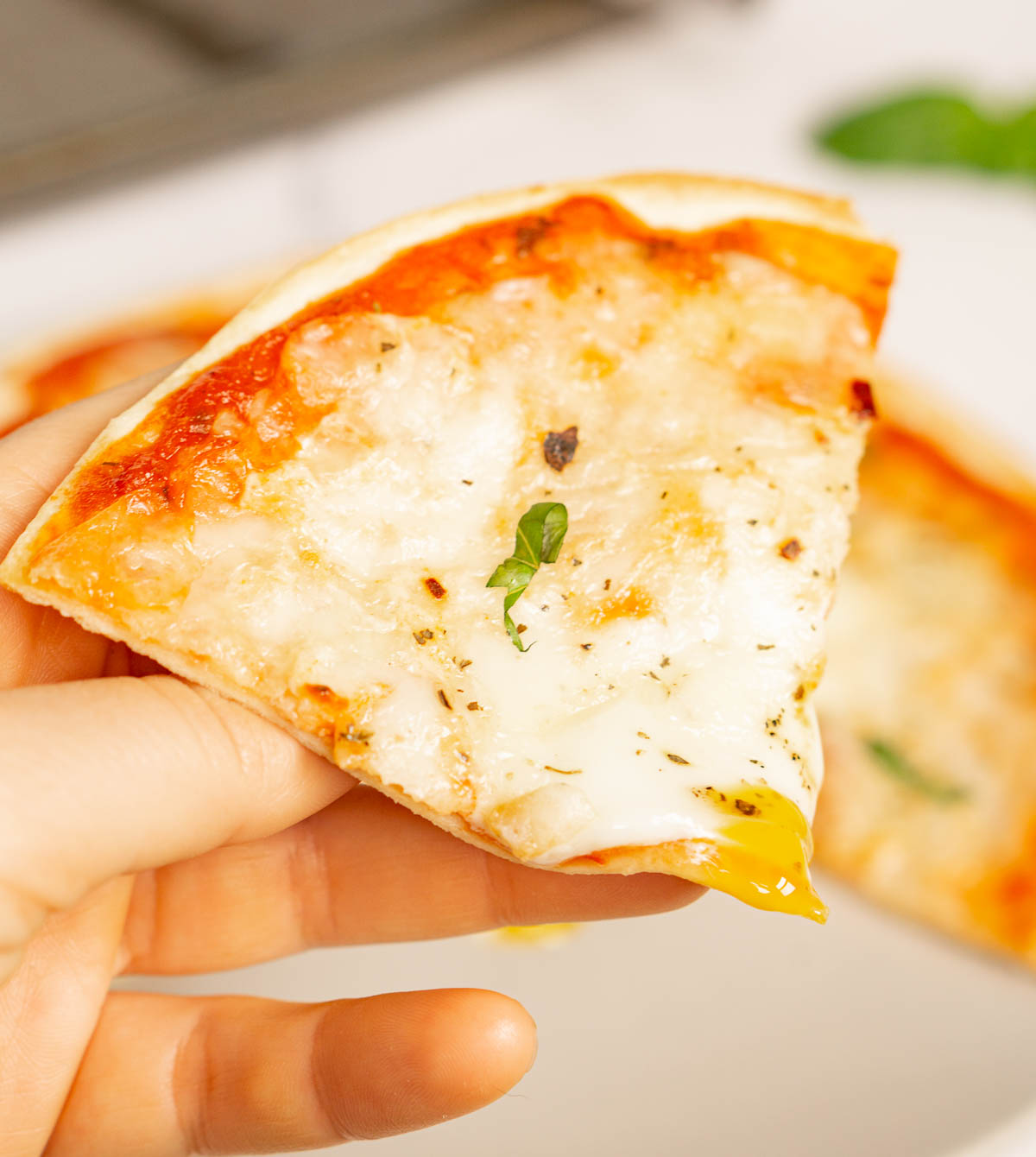 Hand holding slice of tortilla pizza with egg