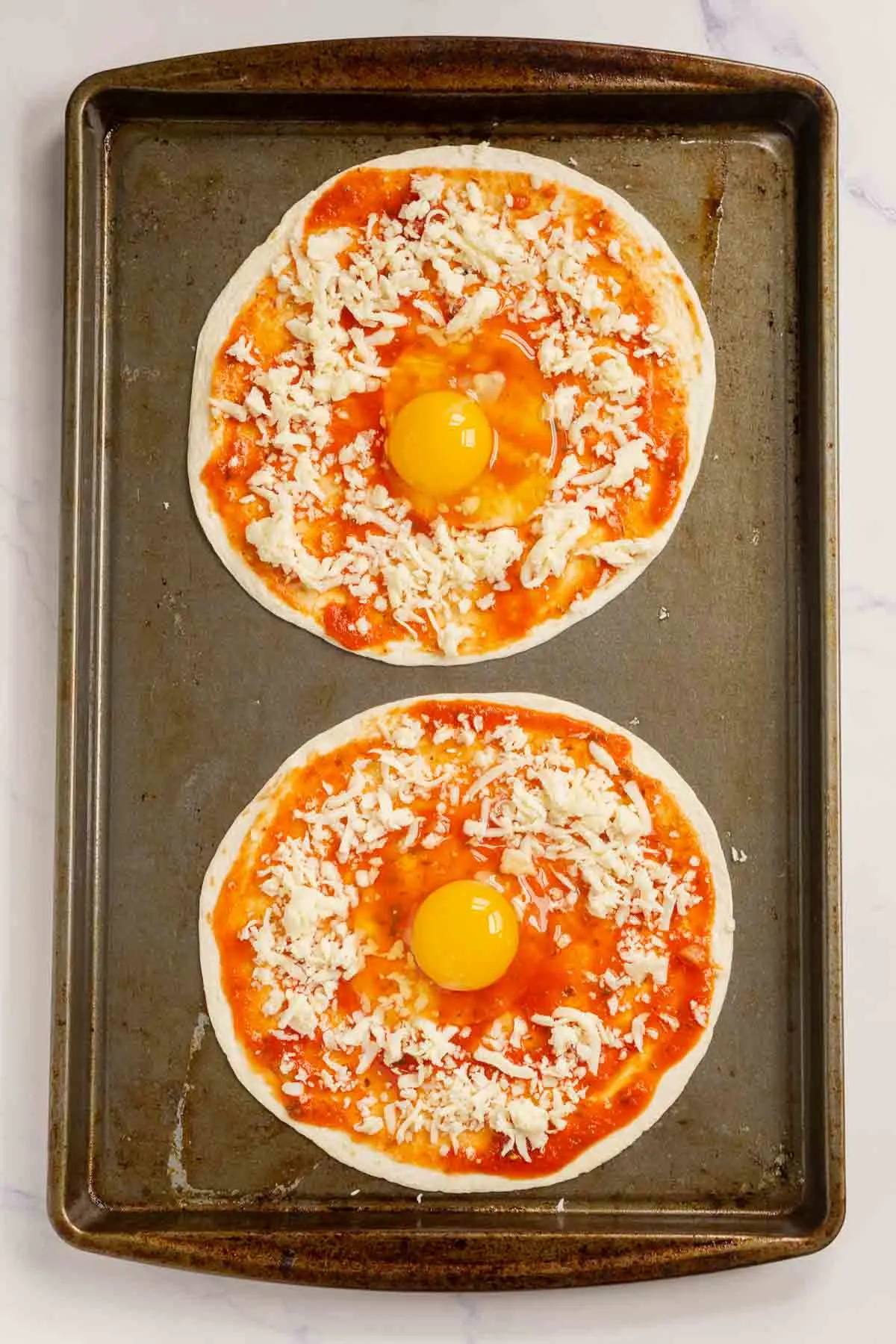 Eggs cracked in the middle of tortilla pizzas
