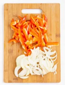 Thinly sliced onion and red pepper on a cutting board