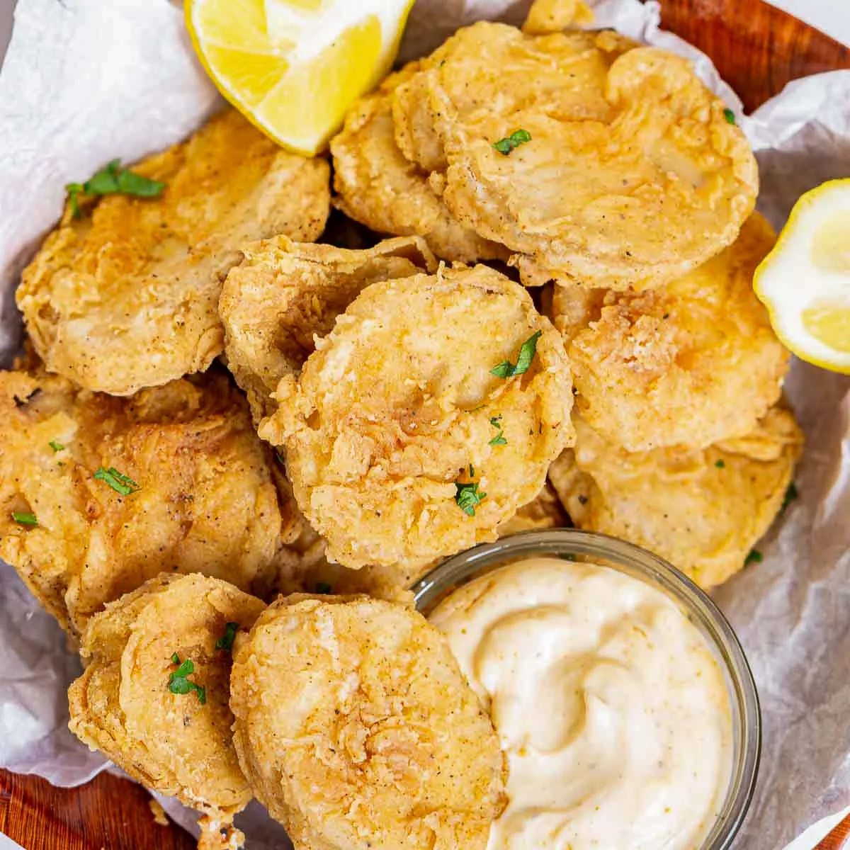 Bowl of fried king oyster mushroom slices with chili mayo dipping sauce and lemon wedges