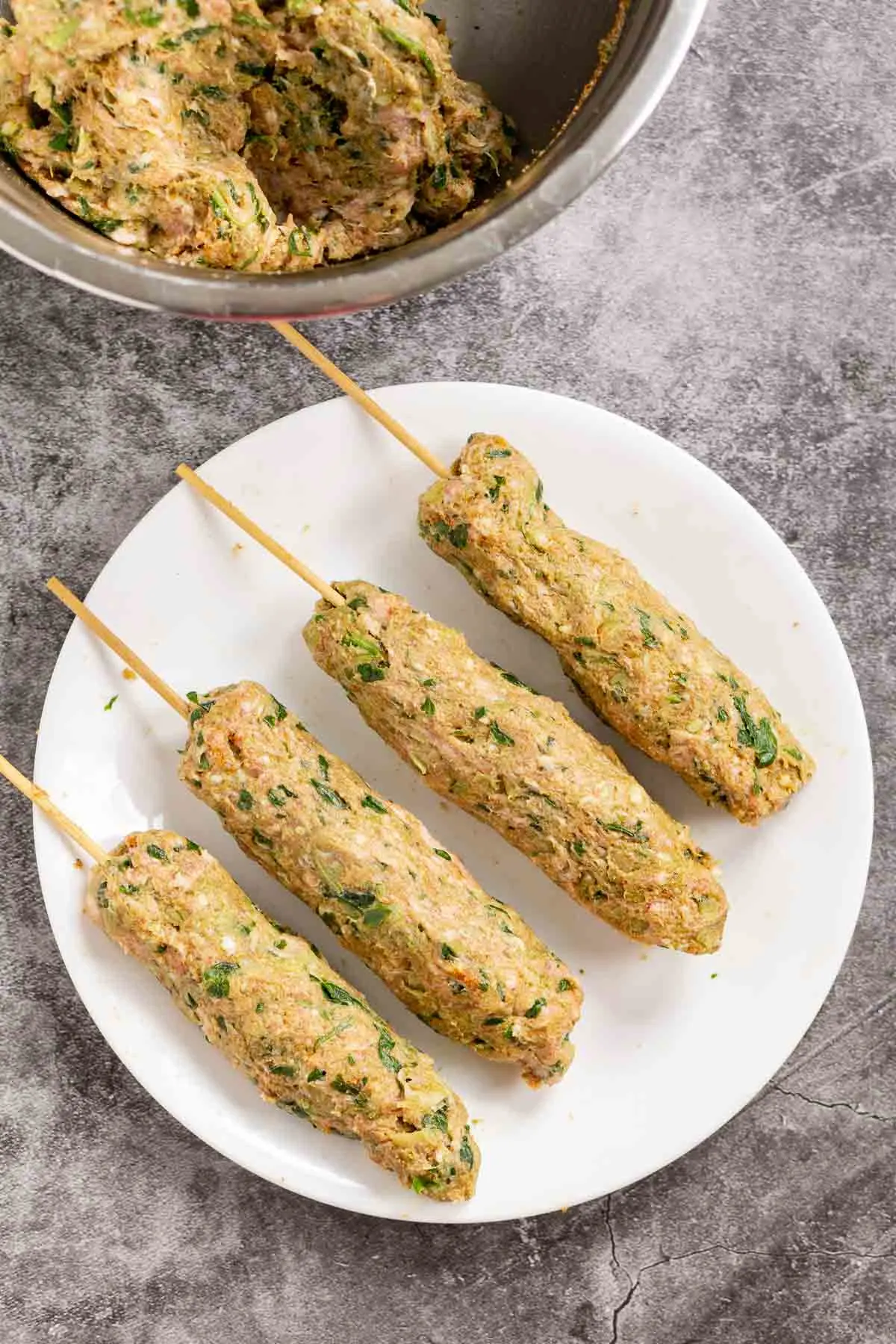 Uncooked kofta kebabs on a skewer to show how to assemble them.