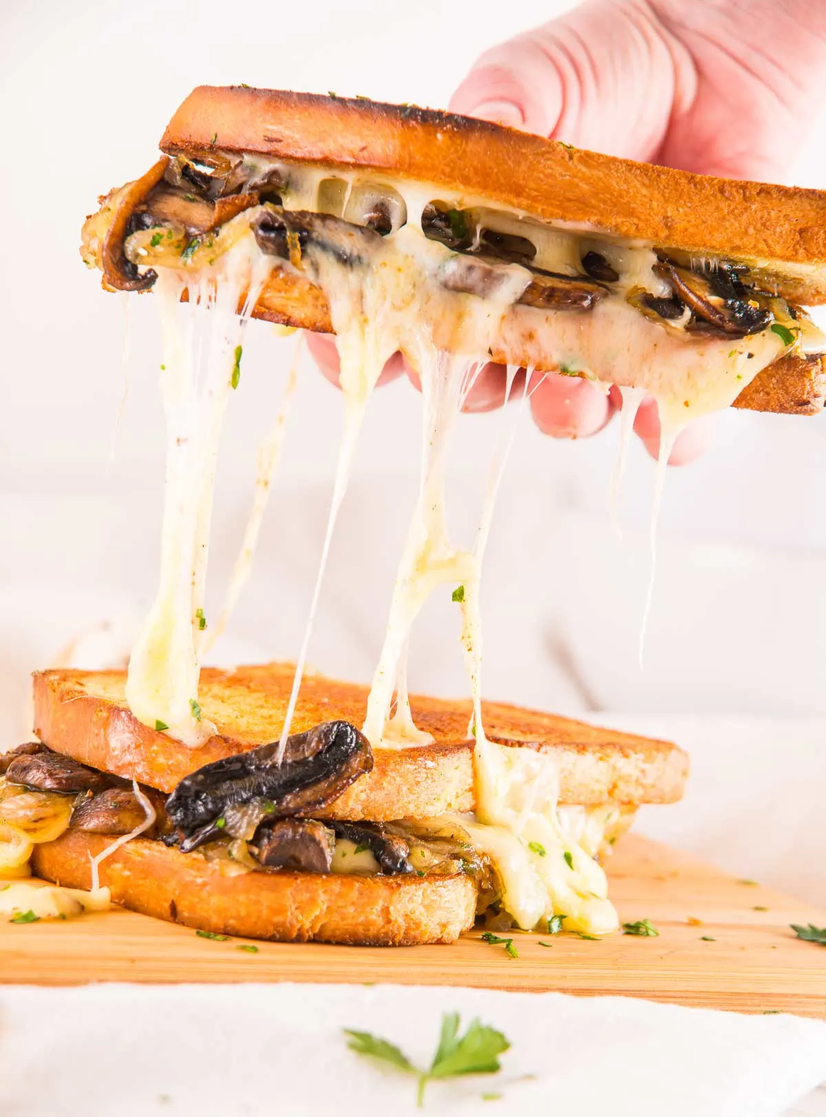 Two mushroom onion grilled cheese sandwiches being pulled apart