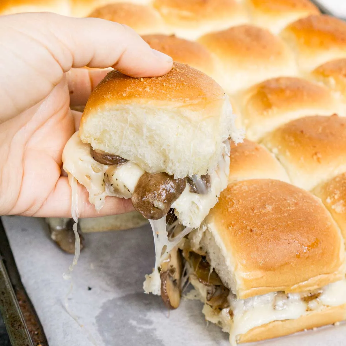 Hand pulling a mushroom slider off a tray