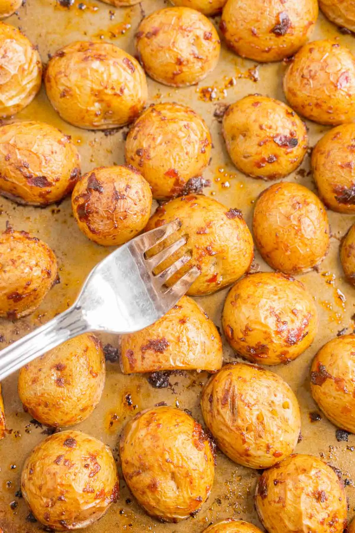 Fork piercing roasted potatoes to show that it is cooked