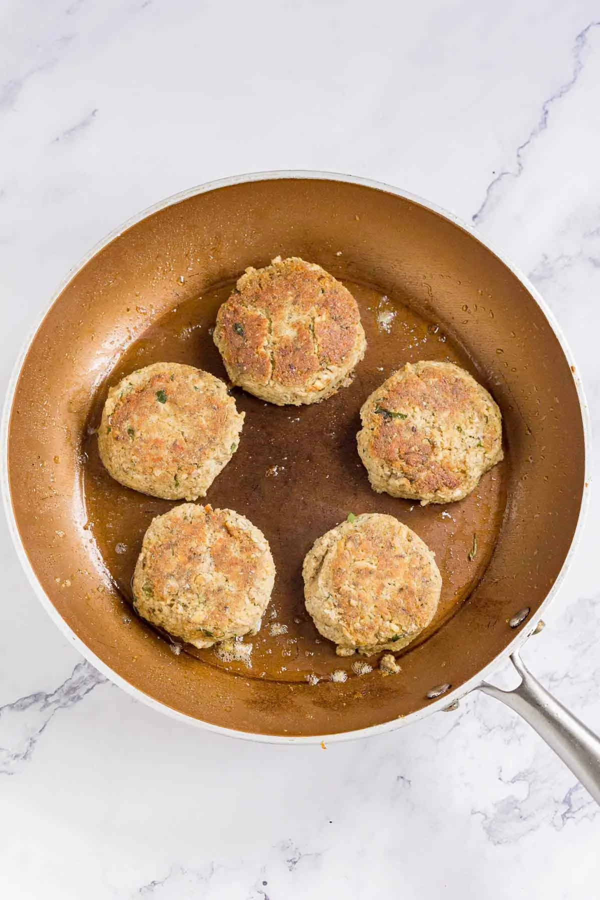 Cooking sardine cakes in a skillet