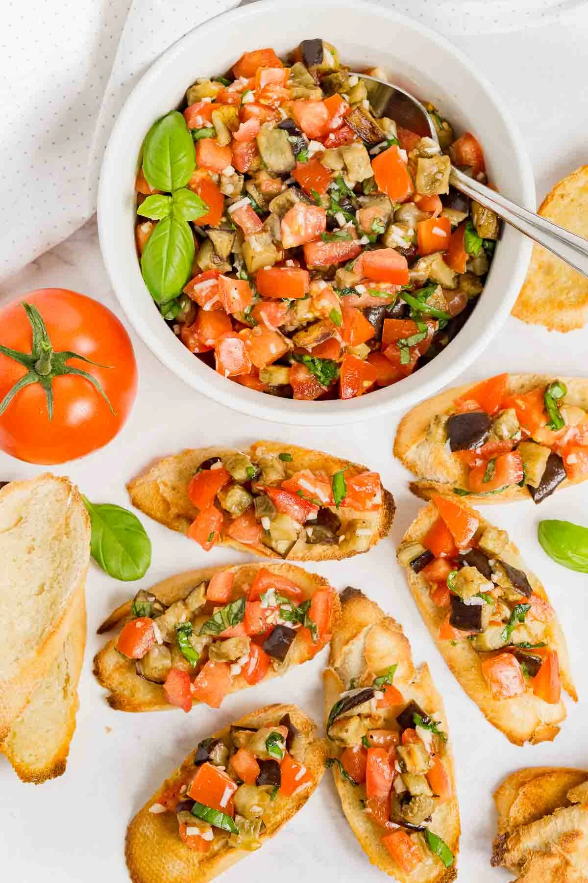 Overhead picture of a bowl of eggplant bruschetta and bruschetta appetizer on crostini