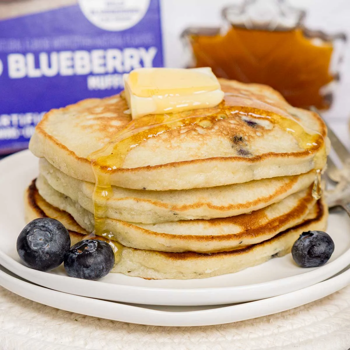 Stack of blueberry pancakes with butter and syrup on top