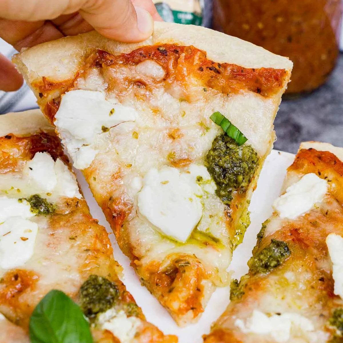Hand holding slice of goat cheese pizza