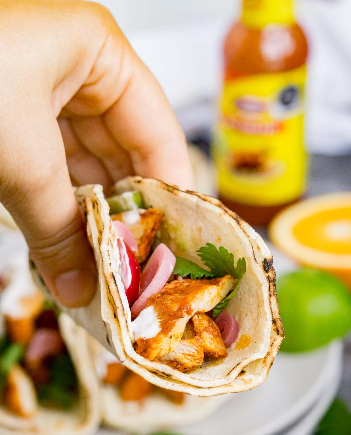 Hand holding a taco with achiote chicken