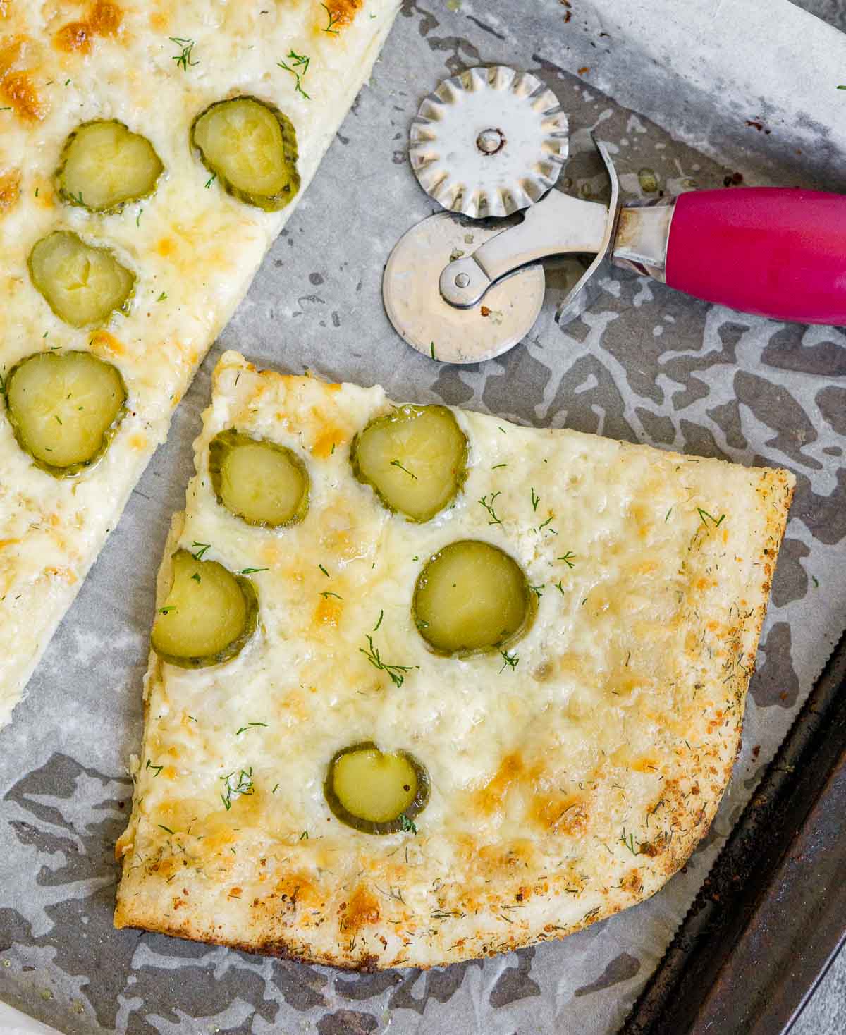 Slice of dill pickle pizza on a baking sheet