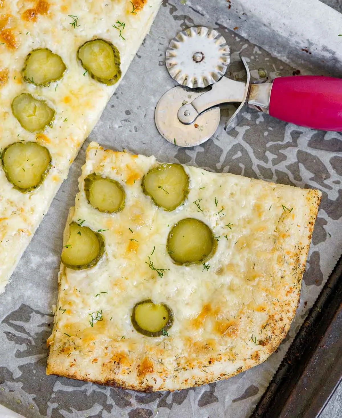 Slice of dill pickle pizza on a baking sheet