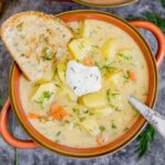 Bowl of potato dill soup with sour cream garnish and a slice of bread