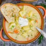 Bowl of potato dill soup with sour cream garnish and a slice of bread