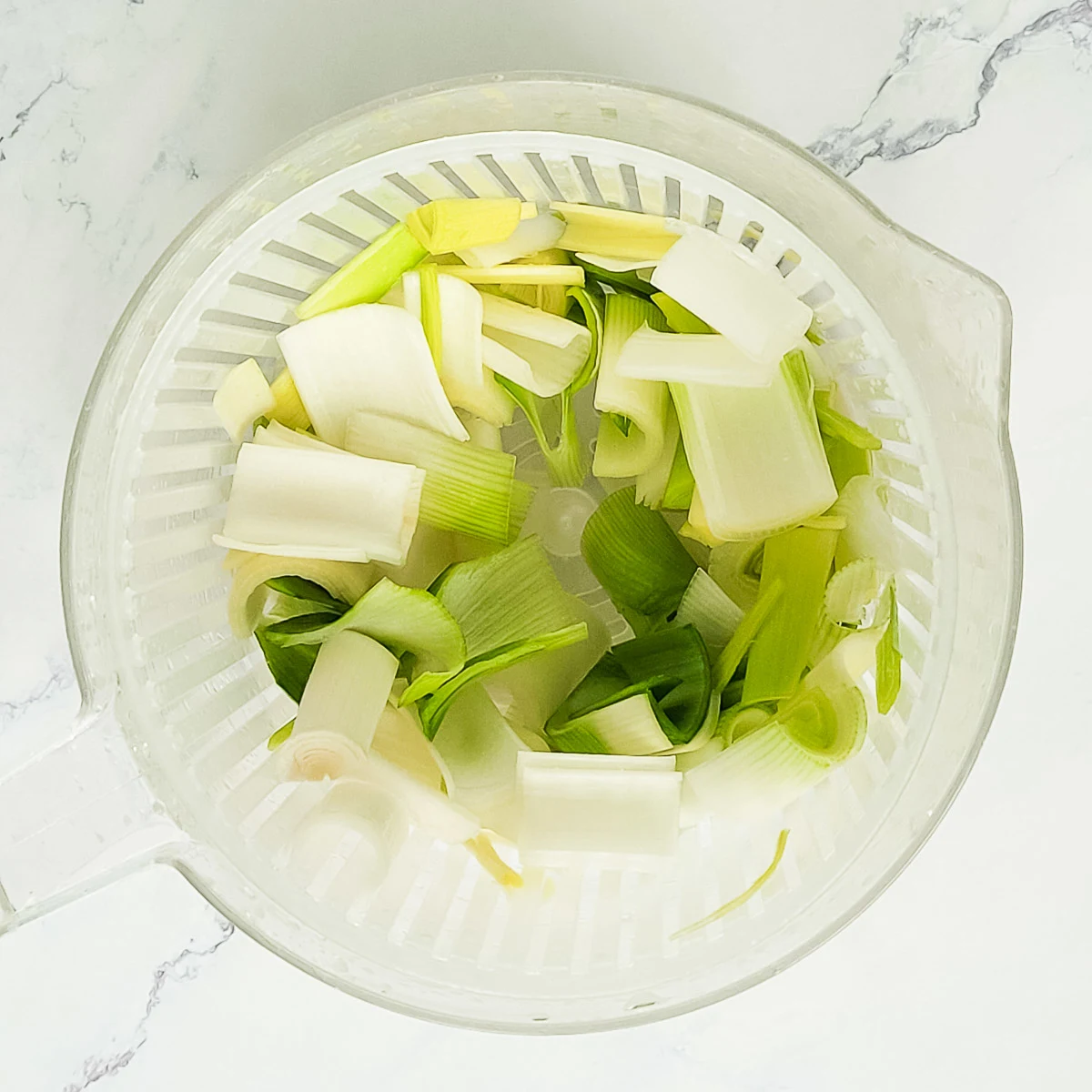 Chopped cleaned leeks in a salad spinner