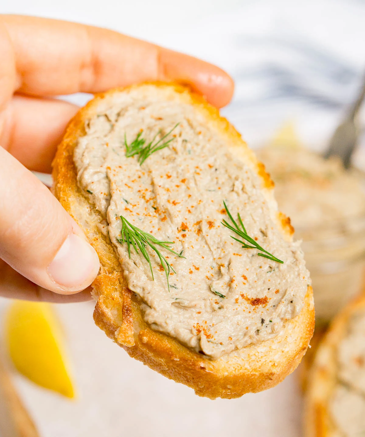 Hand holding sardine toast made with sardine pate
