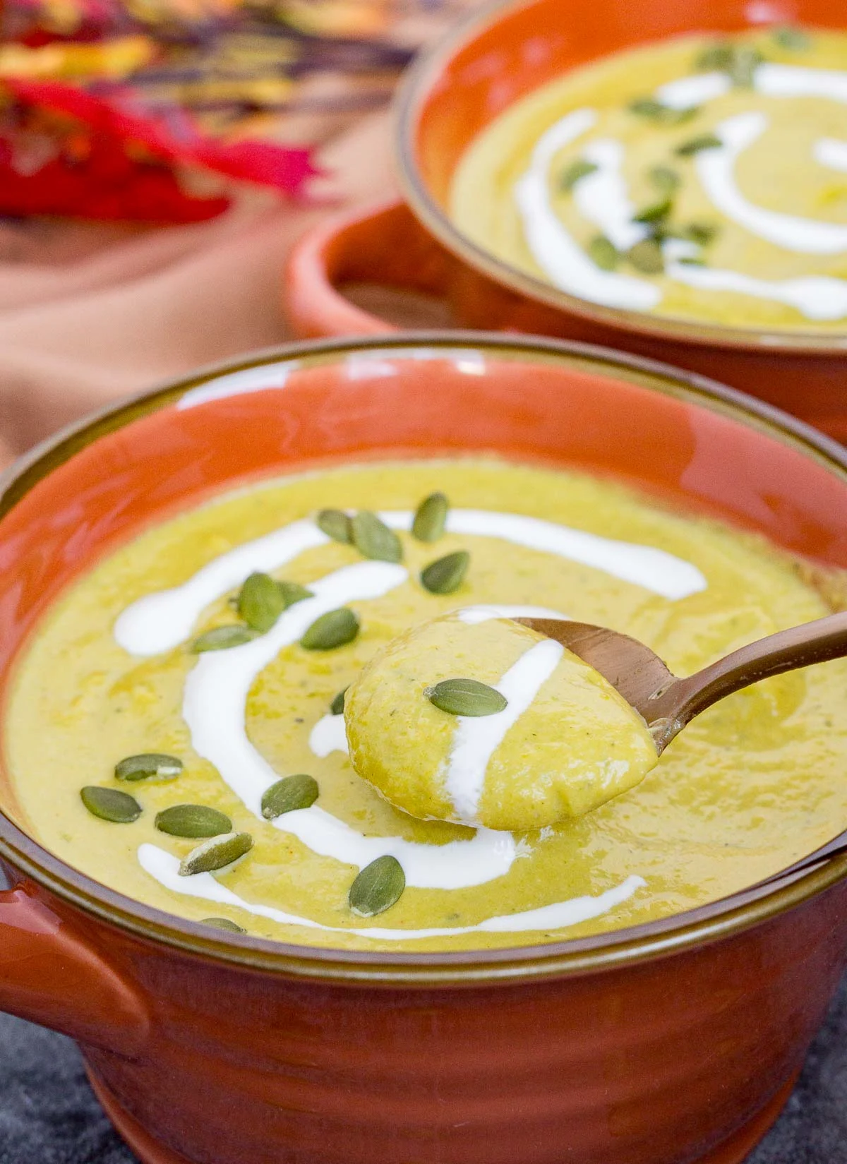 Spoonful of pumpkin leek soup garnished with sour cream and pepitas