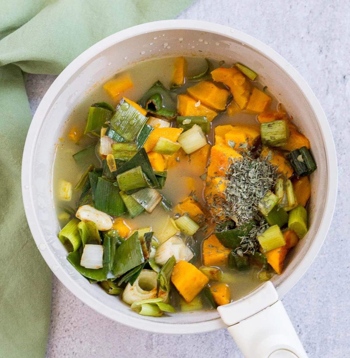 Roasted pumpkin, leeks, broth, and thyme added to a soup pot
